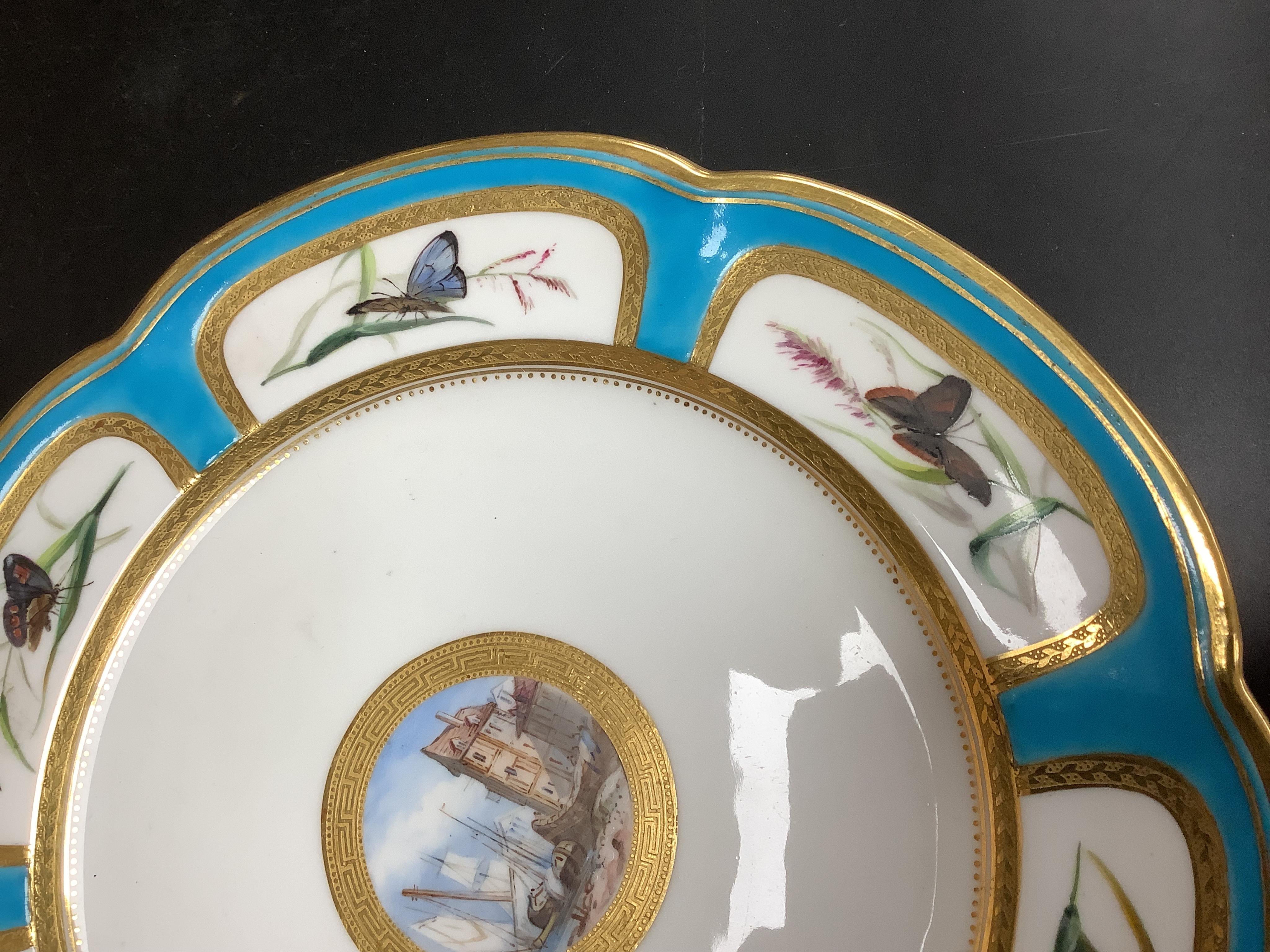 A Minton turquoise and gilt cabinet plate, decorated with butterflies and central continental harbour scene, 24cm diameter.